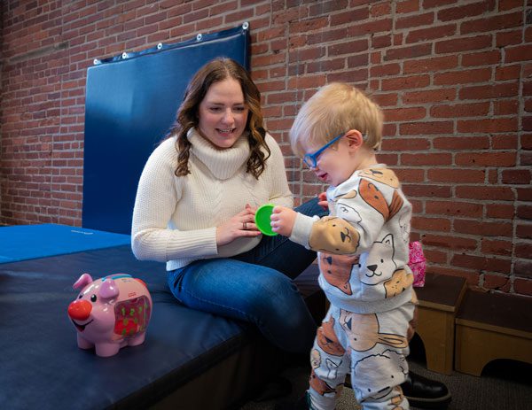 Woman and child play with toys on mat.