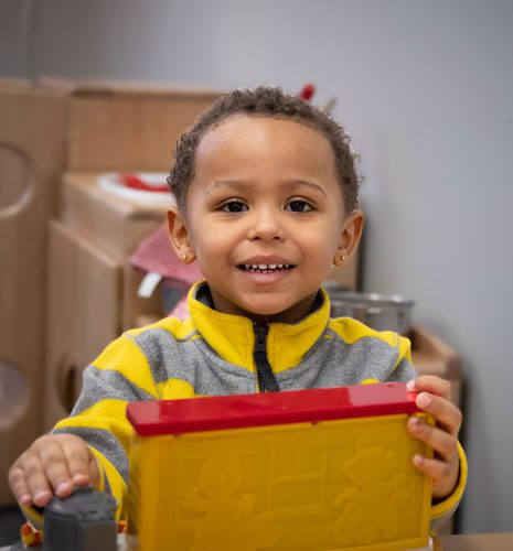 Smiling girl playing with a toy.