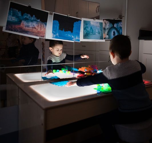 Two children play with light table and toys.